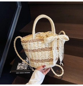 Detail of woven straw bucket bag featuring beige lace bow and drawstring inner lining