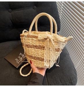 Detail of woven straw bucket bag featuring cream lace bow and drawstring liner