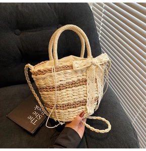 Detail of woven straw bucket bag with beige lace bow and drawstring liner on velvet