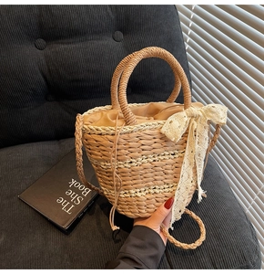 Detail of hand-woven straw bucket bag with lace bow and drawstring liner in natural light