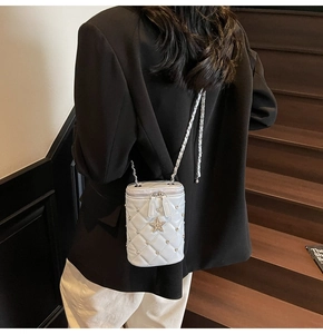 Vue détaillée du sac cylindrique blanc matelassé avec étoile et bandoulière chaîne