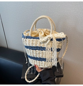 Close-up of woven straw bucket bag featuring a white lace bow and drawstring closure