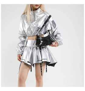 Detailed view of black patent leather square bag with silver buckles on silver outfit
