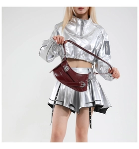 Detail view of burgundy leather shoulder bag with silver buckle worn by a model