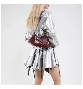 Detail of dark red crescent shoulder bag with buckle straps and glossy leather finish