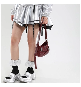 Detail of dark red patent leather handbag with buckles and metal rivets on model