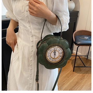 Detail of flower-shaped dark green leather clock handbag worn with a white vintage dress