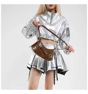 Detailed view of a brown glossy leather avant-garde handbag with silver buckle straps