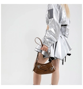 Detail of a brown glossy leather half-moon bag featuring silver metal buckles and straps