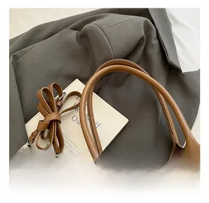 Detail of comfortable brown leather handles and silver metal rings on a commuter tote