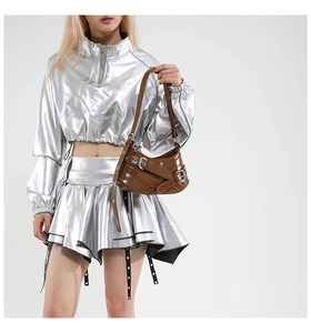 Close-up of brown glossy leather underarm bag with decorative metal buckles and Y2K retro straps