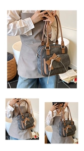 Detail view of large grey canvas shoulder bag with brown bow knot and silver metal rings