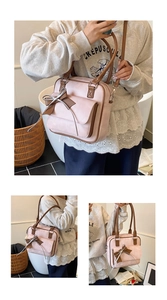Detail shot of a pink shoulder bag with a brown bow and contrast stitching trim