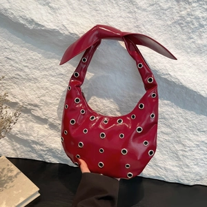 Deep red patent leather crescent hobo bag with oversized bow and silver grommet studs