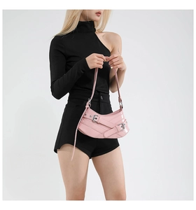 Close-up of pink patent leather handbag featuring decorative metal buckles and Y2K style