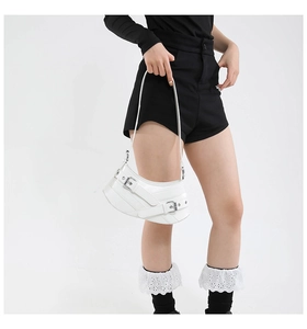 Detailed view of white asymmetrical shoulder bag with silver metallic buckle straps