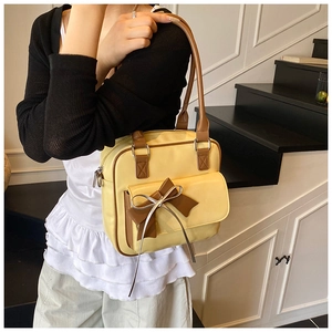 Detail of yellow shoulder bag with large brown bow and stitching for vintage aesthetic