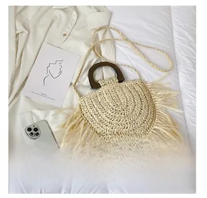 Detail of straw woven bag featuring fringe tassels and a dark wooden D-shaped handle