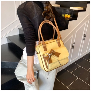 Detail of a yellow shoulder bag featuring a large brown bow and durable PU leather texture