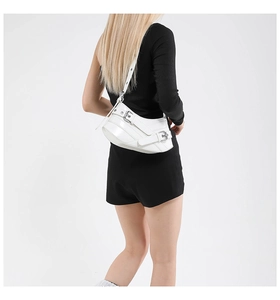 Detail of white leather crescent bag with metal buckle straps and punk aesthetic