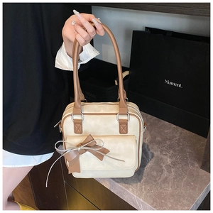 Detail view of beige shoulder bag with brown trim and vintage bow decoration