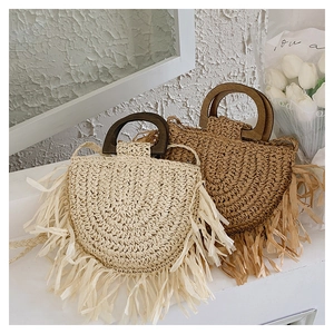 Detailed texture of handmade straw woven bags with wooden handles and raffia fringes
