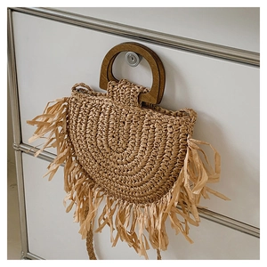 Detail of bohemian straw handbag featuring wood handles and dense fringe tassels