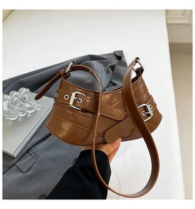 Close-up of dark brown lychee texture leather shoulder bag with silver buckle straps