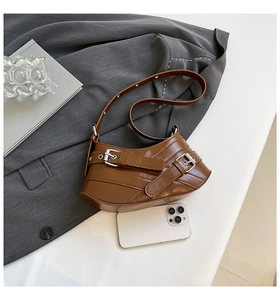 Top view of a brown vintage shoulder bag with buckles on a dark grey trench coat
