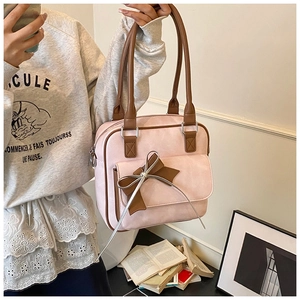 Detail of a light pink underarm bag with a brown bow decoration and stylish top handle