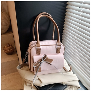 Detail of pink faux leather shoulder bag with brown bow accent and silver ribbon