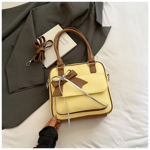 Detailed view of a yellow PU leather tote with brown trim and decorative bow accent