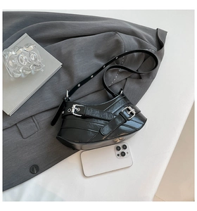 Macro detail of glossy black subculture shoulder bag with silver metal buckles