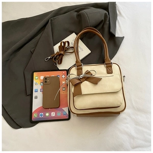 Detail of vintage beige underarm bag with brown bow accent and adjustable strap