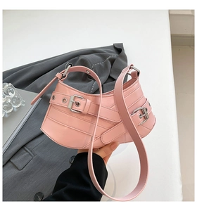 Detail of pink crescent bag featuring punk-style silver buckles and smooth PU leather