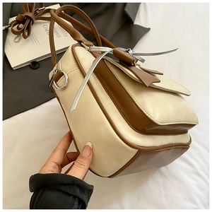 Close-up of contrast color handbag with leather bow detail and silver metal rings