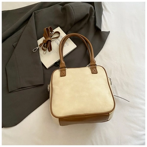 Detail of a cream and brown contrast shoulder bag showing leather texture and straps