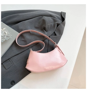 Flat lay of pink leather shoulder bag with metallic strap on grey office blazer background