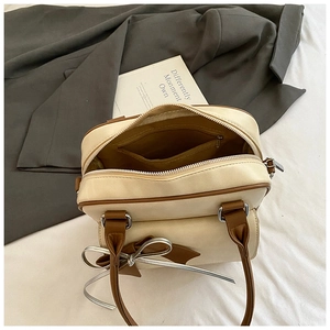 Detailed view of the interior zip pocket and dual zipper of the cream leather handbag