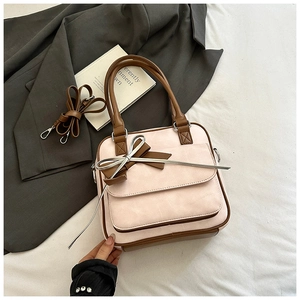 Detail of Korean style pink handbag featuring a leather bow and detachable brown shoulder strap