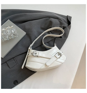Macro shot of white irregular biker shoulder bag with silver buckles and stitch details
