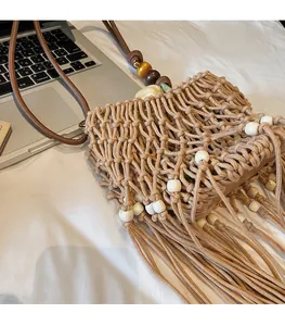 Detail of woven straw bag with hollow crochet pattern, white beads and long tassels