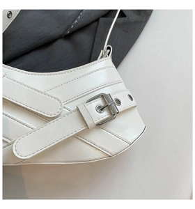 Detailed close-up of cream leather shoulder bag with silver buckle and fine stitching
