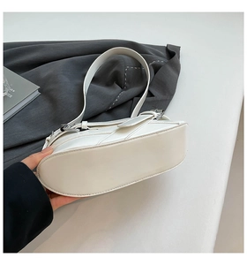 Detail view of the smooth white leather bottom and silver buckle on the underarm bag