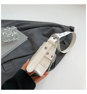 Detailed close-up of white leather handbag featuring silver metal grommets and buckles