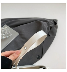 Detail of white leather bag handle featuring precision stitching and silver metal eyelet