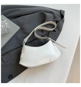 Close-up of white minimalist crescent bag on a gray suit with adjustable silver buckle