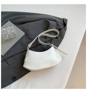 Detailed view of a white crescent shoulder bag with smooth leather and adjustable strap