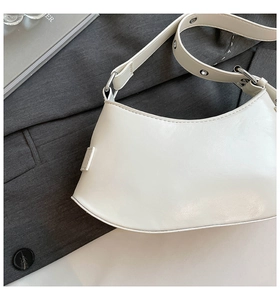 Detail view of a white leather hobo bag with metal grommets on the shoulder strap
