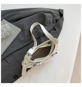 Close-up of white leather handbag interior showing zipper pocket and metallic buckle detail